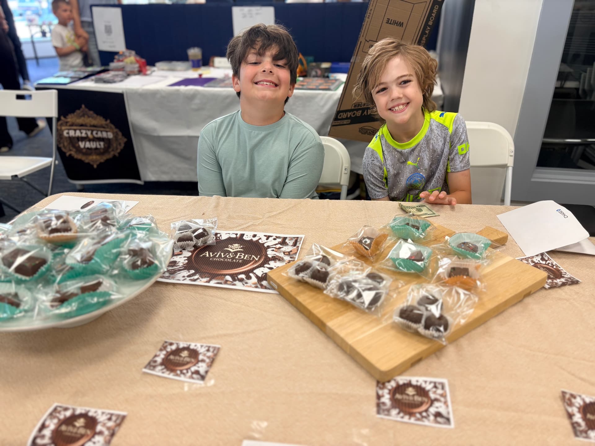 Aviv and Ben smiling behind their chocolate booth